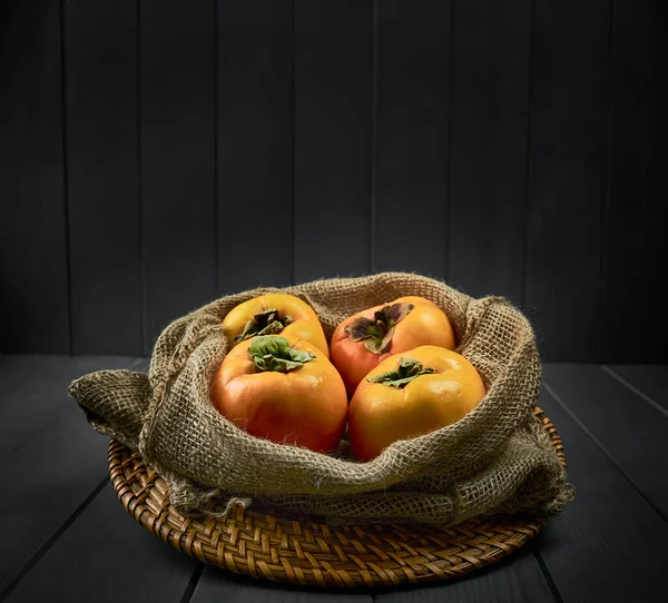 Sack Persimmons Wicker Plate Gray Wooden Background — Stock Photo, Image