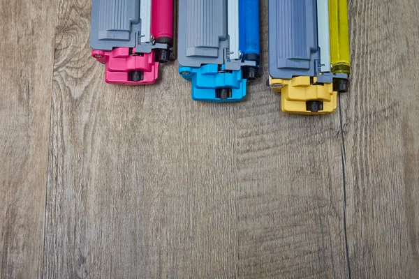 Three toner cartridges for color laser printer stacked on wooden table