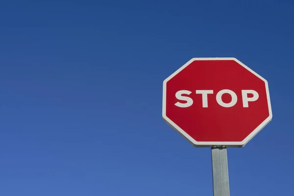 Vertical traffic stop sign, in red and white tones, on blue background