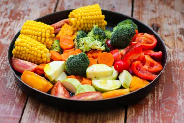 Yuvarlak pişirme tavasında karışık sebzeler ahşap masada pişmesini bekliyor, kırsal tarzda, süper sağlıklı, yakın çekim, üst görünüm