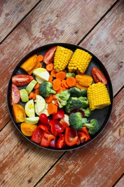 Yuvarlak pişirme tavasında karışık sebzeler ahşap masada pişmesini bekliyor, kırsal tarzda, süper sağlıklı, yakın çekim, üst görünüm