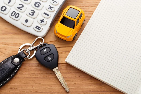 Car key with calculator and notebook on wood table — Stock Photo, Image