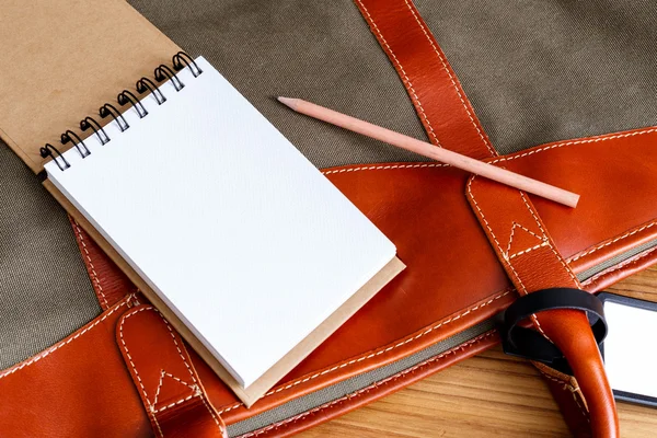 Cuaderno con lápiz en la bolsa de viaje — Foto de Stock