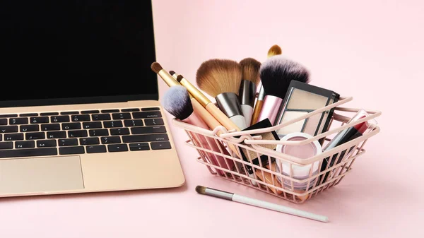 Makeup beauty online shopping business concept with cosmetic products in shopping basket on pastel pink background