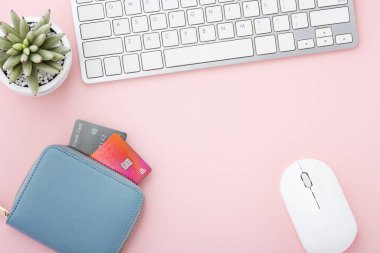 Pembe zemin üzerinde kredi kartı ve bilgisayar klavyesi olan çanta, çevrimiçi ödeme veya alışveriş konsepti, kopyalama alanı olan daire