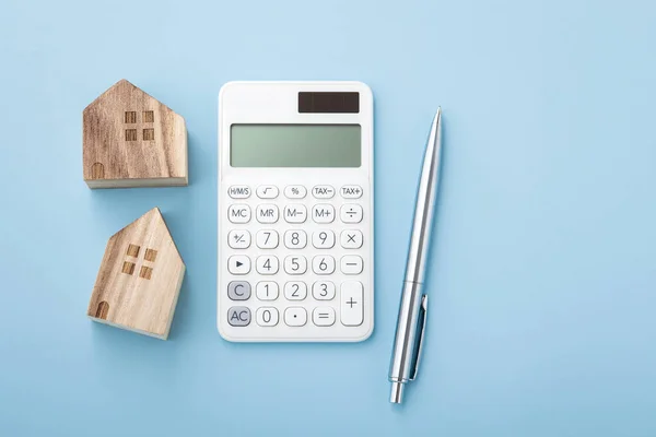 具有房屋模型和钢笔的计算器 蓝色背景的住房融资概念 顶视图 — 图库照片