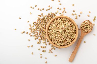 Beyaz arka planda kaşıkla ahşap kasede karabuğday, sağlıklı beslenme, çiğ yemek.