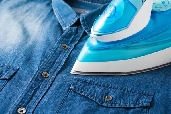 Ironing blue jean shirt — Stock Photo, Image