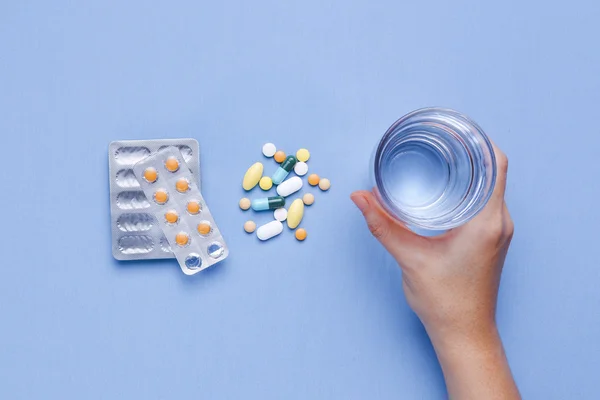 Mano sosteniendo vaso de agua con pastillas —  Fotos de Stock