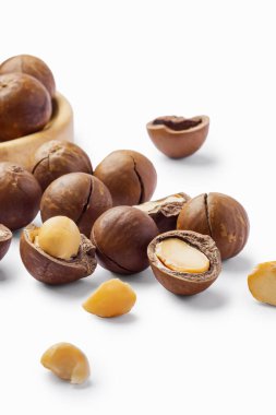 Çatlak fındıklı ve kabuklu Macadamia fındıkları beyaz arka planda izole edilmiş, yakın plan.