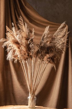 Kahverengi arka planda cam vazoda bir buket yabani çiçek.