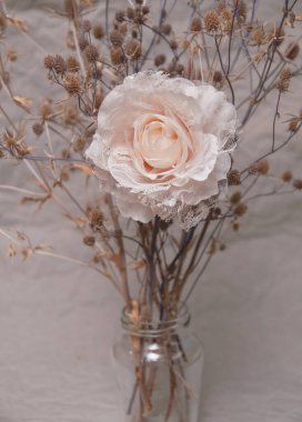 Gri arkaplanda devedikeni olan pastel renklerde yapay bir gül.