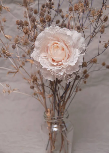 Gri arkaplanda devedikeni olan pastel renklerde yapay bir gül.