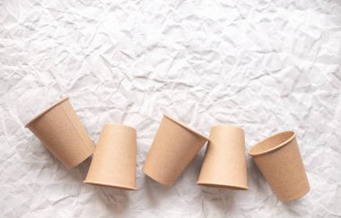 Geometrik desenli gri buruşmuş kağıda konmuş tek kullanımlık kağıt bardaklar.