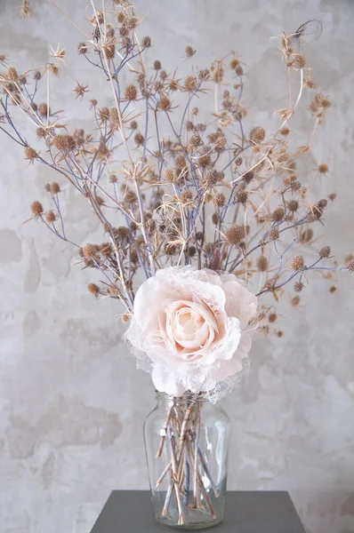 bouquet of dried wild flowers on the background of a concrete wall with an artificial rose