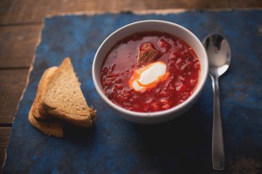 Ahşap bir masada ekşi krema ve ekmek ile geleneksel Ukrayna yemeği çorbası.