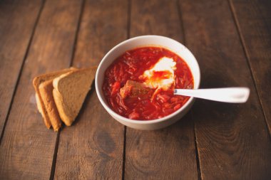 Ahşap bir masada ekşi krema ve ekmek ile geleneksel Ukrayna yemeği çorbası.