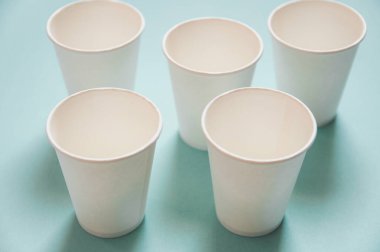 Tek kullanımlık beyaz kraft kağıt bardaklar kağıt mavi arka planda duruyor