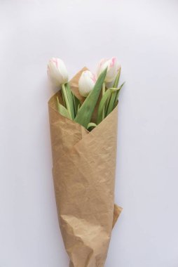 Beyaz bir kağıda sarılı beyaz lale çiçekleri hediye demeti.