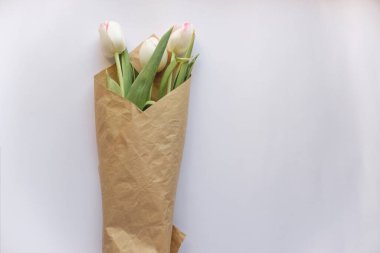 Beyaz bir kağıda sarılı beyaz lale çiçekleri hediye demeti.