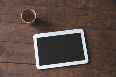 Masasında tablet bilgisayar ve tek kullanımlık kahve olan modern ofis çalışma alanı. Bir tasarım sunumu veya portföy için.