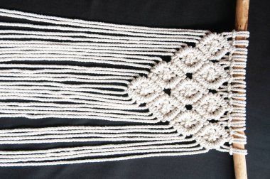 Dekoratif el yapımı pamuklu makrome dekorasyon, siyah arka planda asılı kalmak için hobi. DIY boho ev dekorasyonu, çevre dostu modern örgü. İç mekanda doğal dekorasyon kavramı.