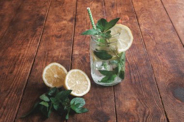 Limon ve nane aromalı yaz turunçgil kokteyli, mohito. Kahverengi ahşap masada limonlu soğuk limonata