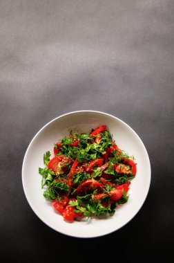 Maydanoz, domates ve dereotlu salata. Beyaz tabakta, arka planda. Kilo vermek için sağlıklı yiyecekler, vejetaryen yemekleri. Siyah arka planda taze sebzeler..