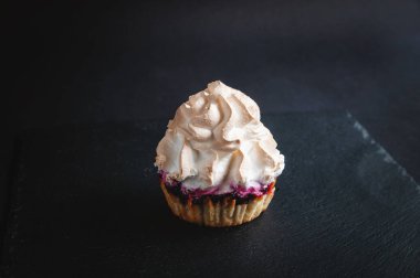 Siyah arka planda kek. Karanlık bir arka planda, meyveli kekler taştan siyah servis tahtasına doluyor..