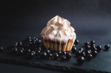 Frenk üzümlü, siyah arka planda kek. Karanlık bir arka planda, meyveli kekler, böğürtlenler ve üzümler servis tahtasında..