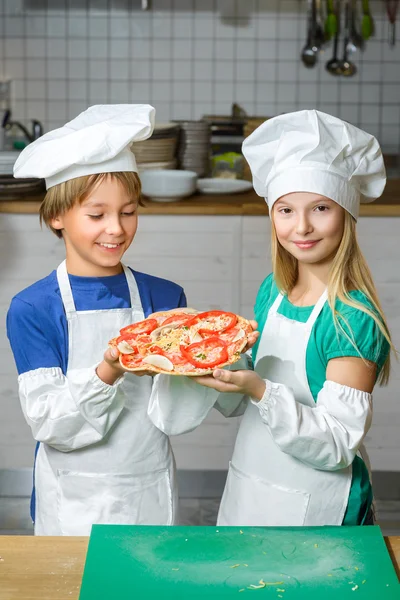 Funny happy chef boy and girl cooking at restaurant kitchen or show pizza