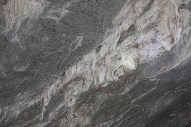 Gri duvarları olan karanlık bir mağaraya bak. Mağaranın taş duvarının yüzeyi. Gri antik taş doku arka planı. Mağarada güzel gri sarkıtlar var. Rusya, Güney Ural, Bashkortostan