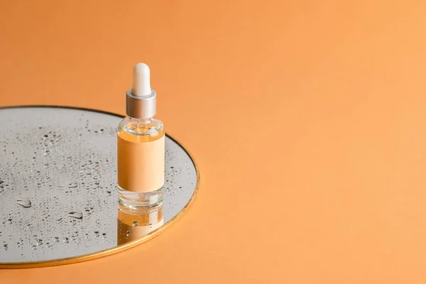 Açık turuncu arka planda damlaları olan bir aynada deri bakımı için pipeti olan şeffaf bir serum şişesi. Sağlık ve güzellik konsepti. Boşluğu kopyala