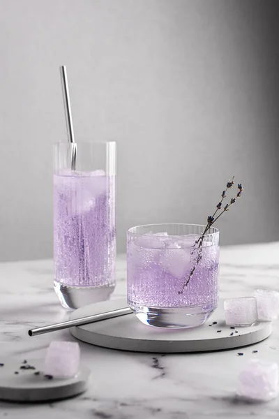 Alkolsüz, lavanta filizi, buz ve köpüklü su dolu, sanat eseri bardaklarında yaz ayları için taze, mor bir kokteyl. Mocktail, sağlıklı yaşam tarzı