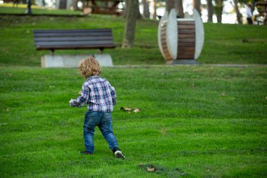 Çocuk güneşli bir günde parkta yürüyor.