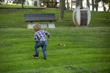 Çocuk güneşli bir günde parkta yürüyor.