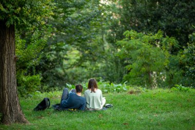 Aşıklar parkta çimlerde oturuyor.