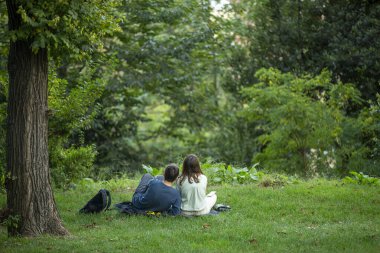 Aşıklar parkta çimlerde oturuyor.