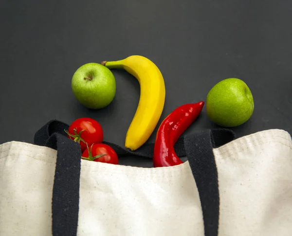 Fresh vegetables and fruits in cloth bag isolated on black background.