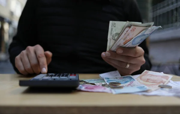 man doing financial transactions with calculator holding money in han