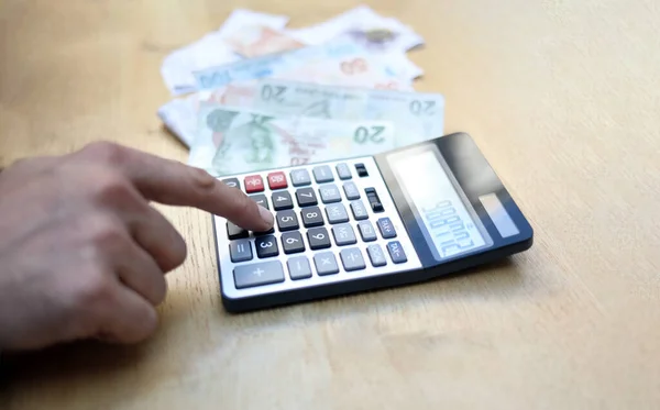 Adam para tutan hesap makinesiyle mali işlem yapıyor.