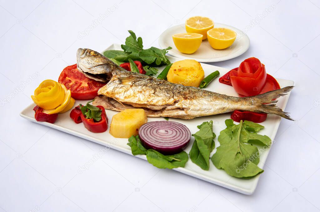 Bluefish and appetizers in white plate, standing on isolated backgroun