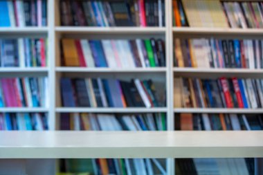 Kitap rafının önünde duran ahşap masa.