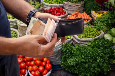 Sebze kontunun önünde cüzdanından para alan adam.