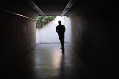 Tünelde scooter kullanan genç adam.