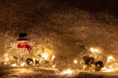 Siyah şapkalı ve kırmızı eşarplı parlak noel kardan adam, parlak peri ışıklarıyla aydınlanır. Noel arifesi ve kutsal gece hazzından önceki aydınlık olarak.