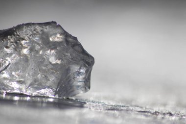 Güneşin altında eriyen donmuş parlak buz kübü soğuk kış mevsiminde kutup bölgesindeki şeffaf buzlarda hoş yansımalarla ısınan güneş ışığında ışıldayan buz kristallerinde suyu dondurur.