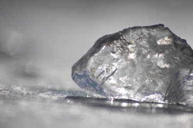 Güneşin altında eriyen donmuş parlak buz kübü soğuk kış mevsiminde kutup bölgesindeki şeffaf buzlarda hoş yansımalarla ısınan güneş ışığında ışıldayan buz kristallerinde suyu dondurur.