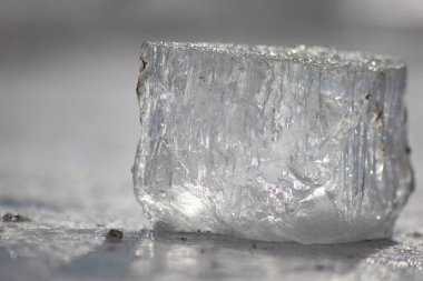 Güneşin altında eriyen donmuş parlak buz kübü soğuk kış mevsiminde kutup bölgesindeki şeffaf buzlarda hoş yansımalarla ısınan güneş ışığında ışıldayan buz kristallerinde suyu dondurur.