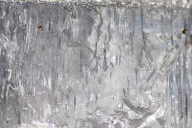 Güneşin altında eriyen donmuş parlak buz kübü soğuk kış mevsiminde kutup bölgesindeki şeffaf buzlarda hoş yansımalarla ısınan güneş ışığında ışıldayan buz kristallerinde suyu dondurur.